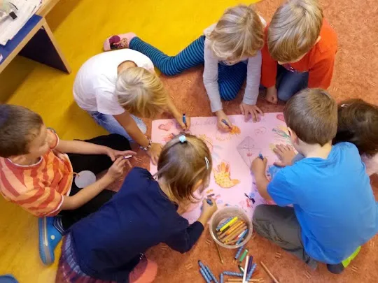 Kinder malen gemeinsam auf dem Boden